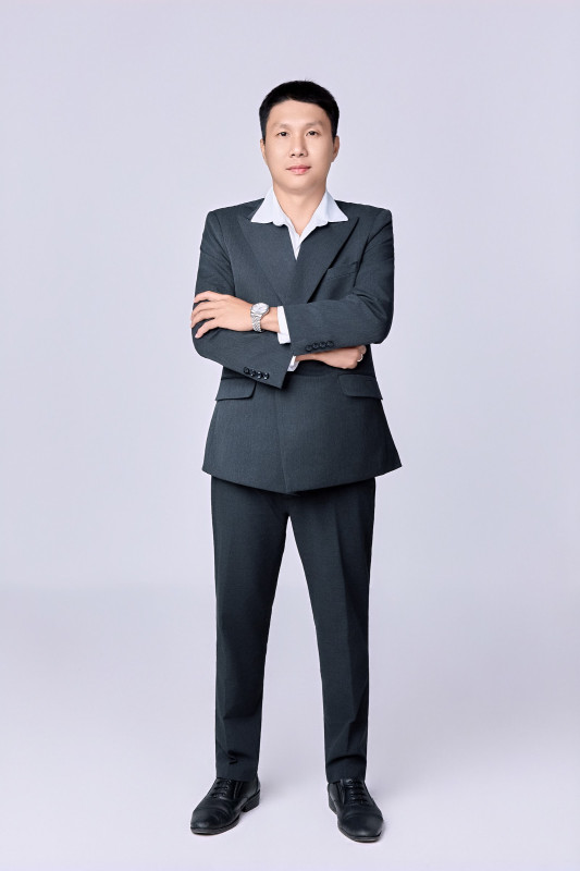 Nam nhân sự đứng khoanh tay, vest xám – ảnh đồng phục công ty Long Xuyên